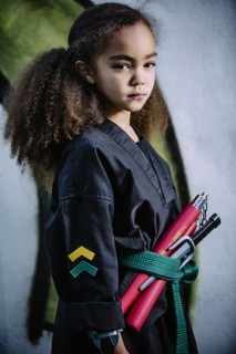 Mixed race girl wearing martial arts uniform with nunchucks