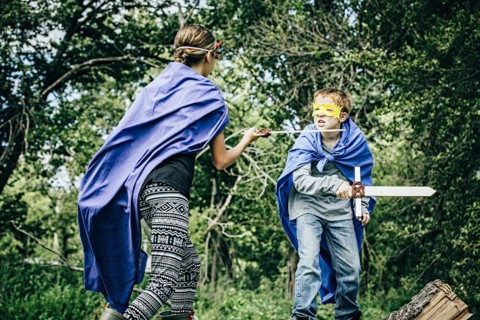 Caucasian children in costumes playing with swords