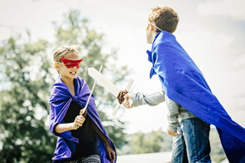 Caucasian children in costumes playing with swords