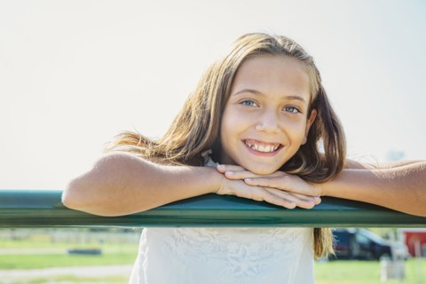 Caucasian girl leaning on farm fence