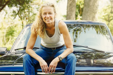Caucasian woman sitting on car hood