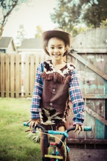 Mixed race girl wearing cowboy costume in backyard