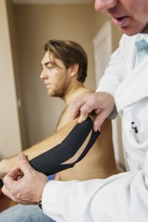 Caucasian doctor applying tape to elbow of patient