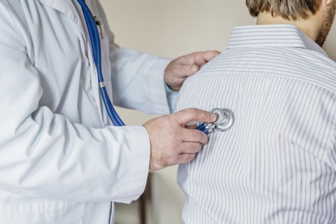 Caucasian doctor listening to heartbeat of patient