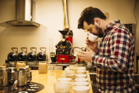 Caucasian barista tasting coffee in coffee shop