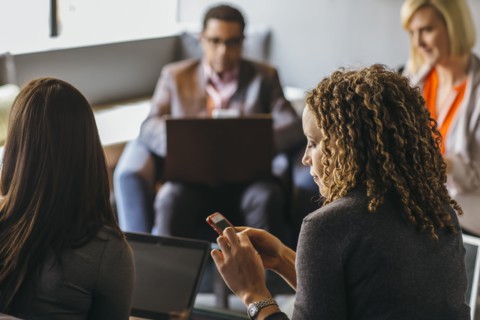 Businesswoman using cell phone in office meeting