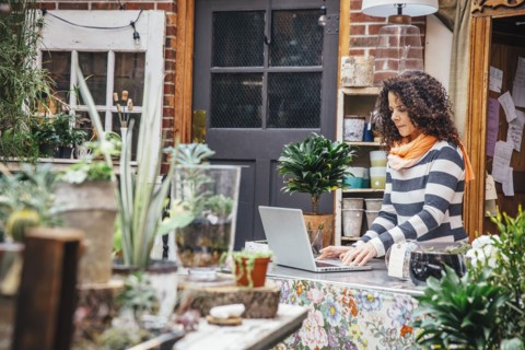 Mixed race employee using laptop in plant nursery