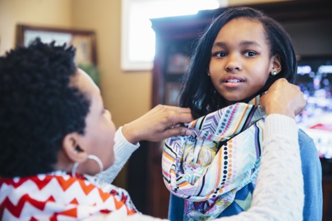 Black mother arranging scarf of daughter