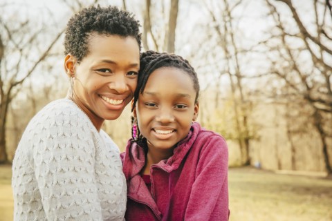 Black mother and daughter smiling outdoors