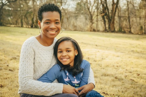 Black mother and daughter sitting outdoors