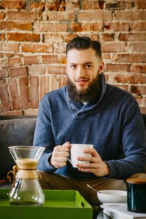 Man drinking coffee on sofa in living room