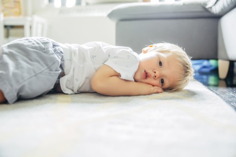 Mixed race boy laying on living room floor