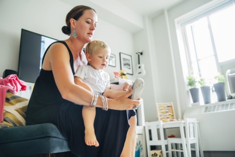 Mother helping son put on shoes in living room