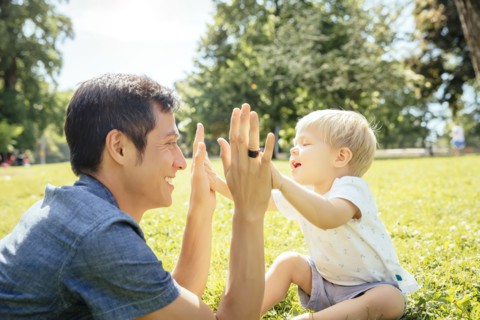 Father and son playing in grass in park