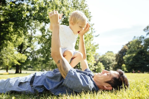Father and son playing in grass in park