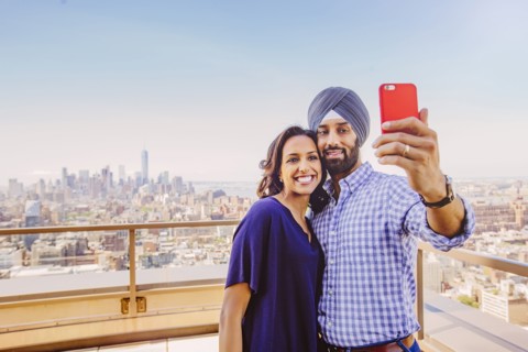 Indian couple taking selfie over New York cityscape