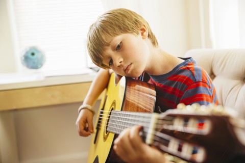 Caucasian boy playing guitar in living room