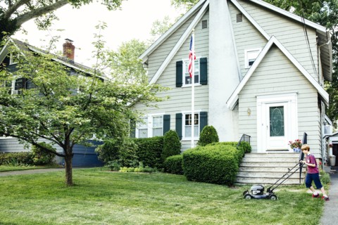 Caucasian boy mowing front lawn