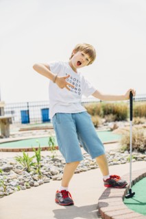 Caucasian boy playing miniature golf on course