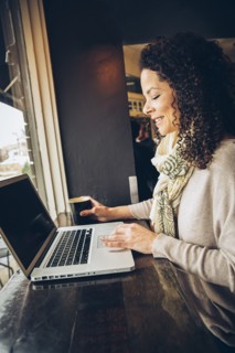 Woman using laptop and drinking coffee in cafe