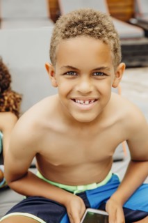 Mixed race boy holding cell phone on patio