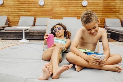 Mixed race children taking selfie with cell phones on patio