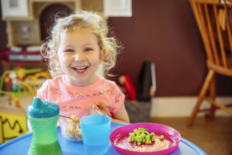 Caucasian girl eating in high chair