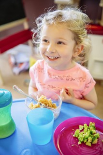 Caucasian girl eating in high chair