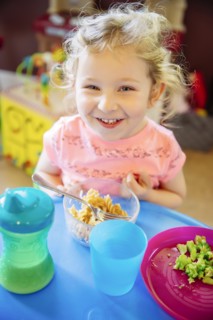 Caucasian girl eating in high chair