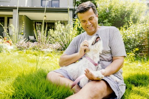 Caucasian man petting dog in grass