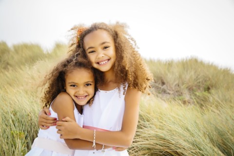 Mixed race sisters hugging outdoors