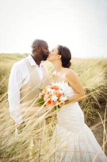 Newlywed couple kissing in grass