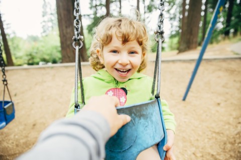 Caucasian mother pushing daughter on swing