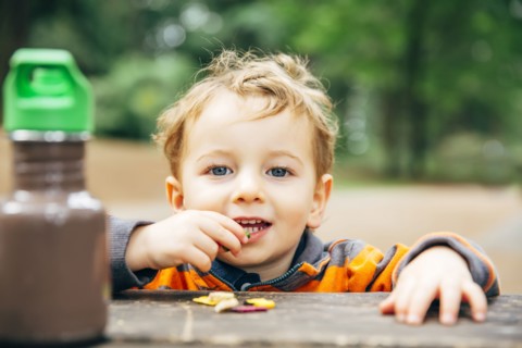 Caucasian boy eating snack at picnic table