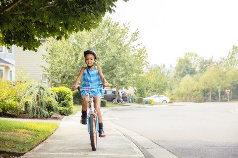 Mixed race girl riding bicycle on sidewalk