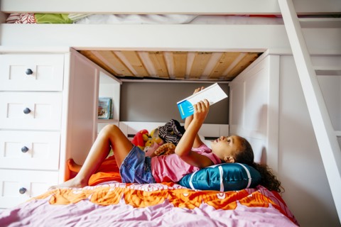 Mixed race girl reading on bed