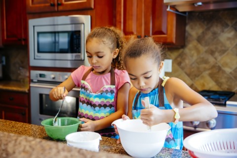 Mixed race sisters cooking in kitchen
