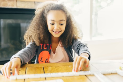 Mixed race girl playing with dominoes