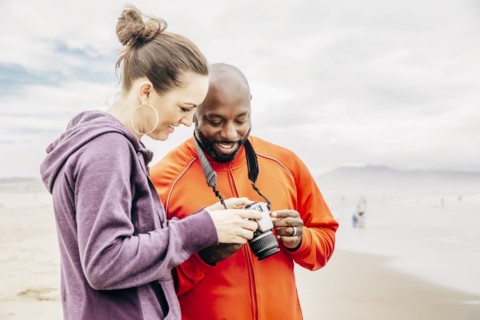 Couple reviewing digital photographs on beach