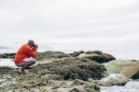Black man photographing on beach