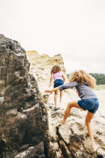 Mixed race sisters climbing on rocks