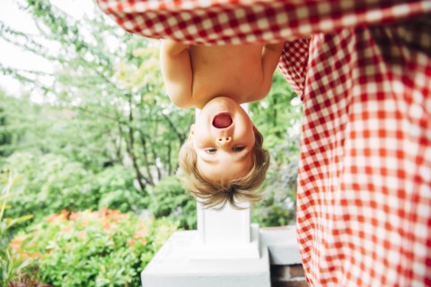 Baby boy hanging upside down outdoors