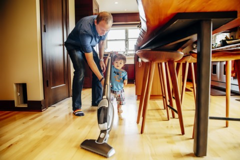 Father and son vacuuming kitchen