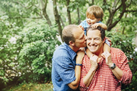 Gay fathers holding baby son outdoors