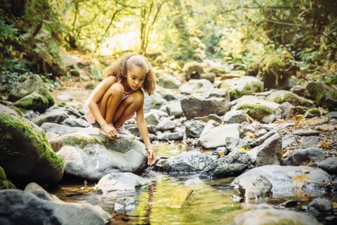Mixed race girl exploring stream