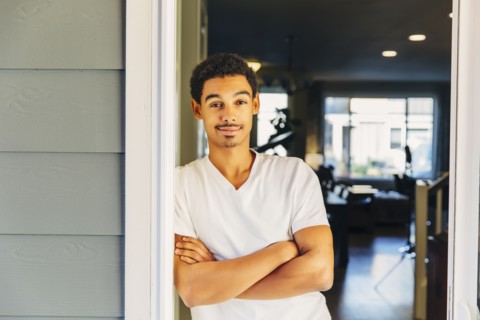 Mixed race man leaning on doorway
