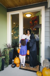 Woman receiving trick-or-treaters on Halloween