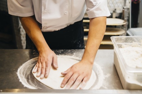 Chef shaping pizza dough in restaurant kitchen