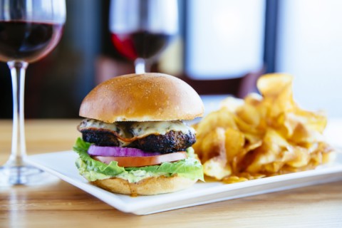 Plate of cheeseburger and chips with wine