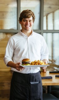 Caucasian waiter carrying cheeseburger and chips in cafe